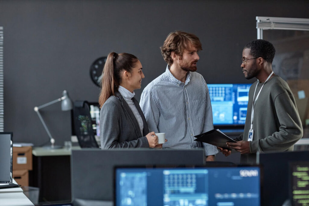 Three young people chatting standing in office